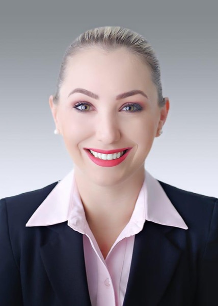 Exemplo de foto de currículo para comissário de voo: enquadramento de busto, sorriso, fundo cinza em degradê e traje social com blazer escuro e camisa clara.